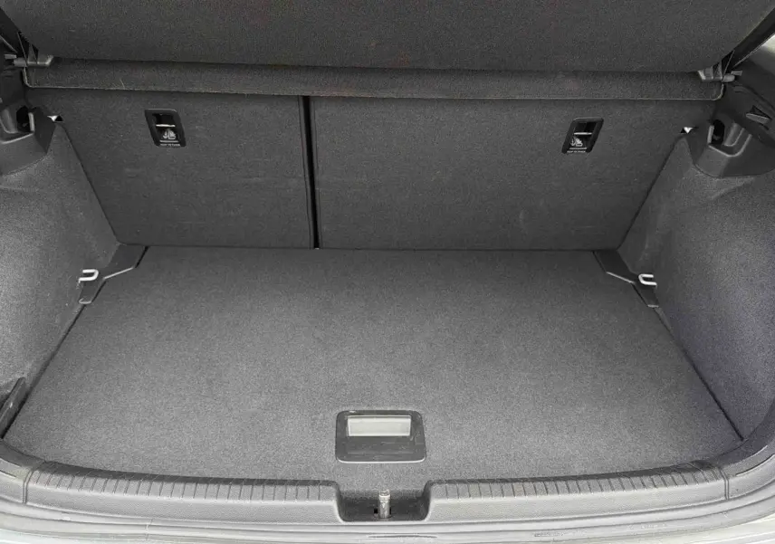 Coffre ouvert d’une Volkswagen Polo grise 2025, vue plongeante sur l’espace de chargement vide et propre.