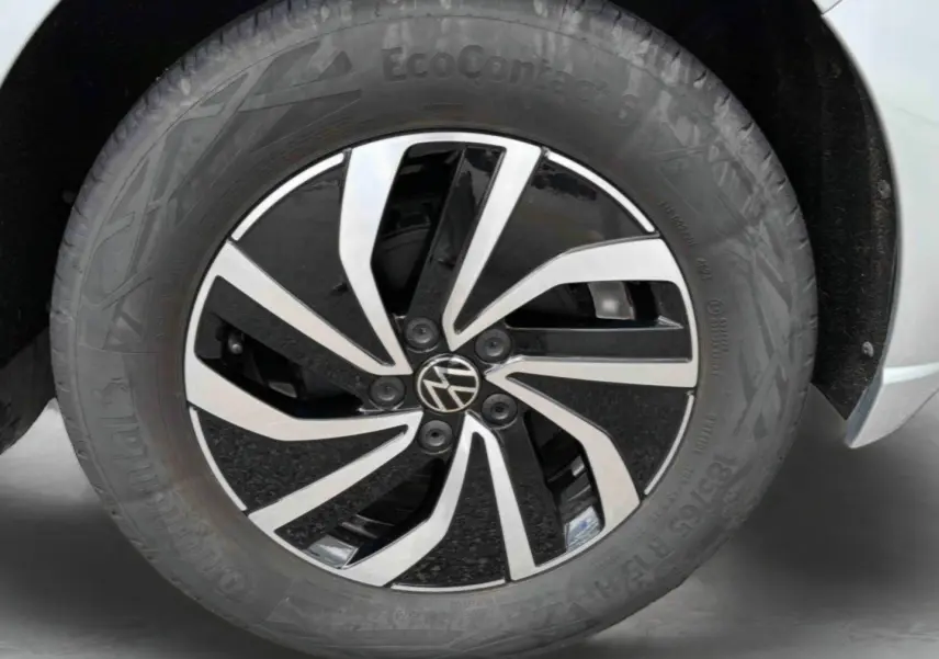 Gros plan sur la jante alliage 15 pouces bicolore avec logo Volkswagen au centre sur une Polo grise.
