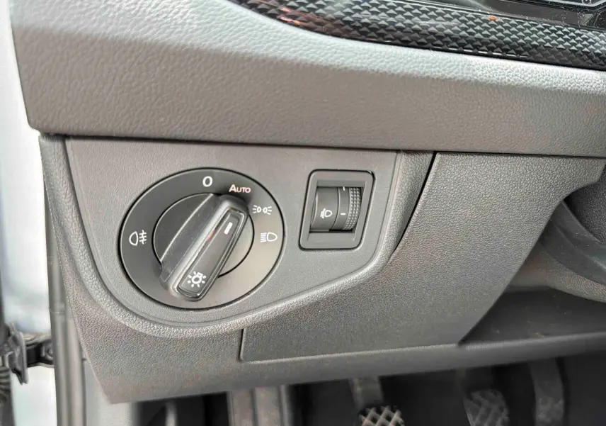 Gros plan sur le panneau de commande des phares dans l'habitacle d'une Volkswagen Polo grise, côté conducteur.