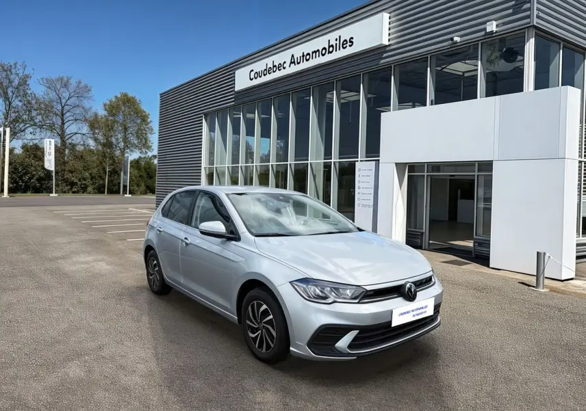 Volkswagen Polo grise vue 3/4 avant droit devant un showroom Coudebec Automobiles, feux LED allumés.
