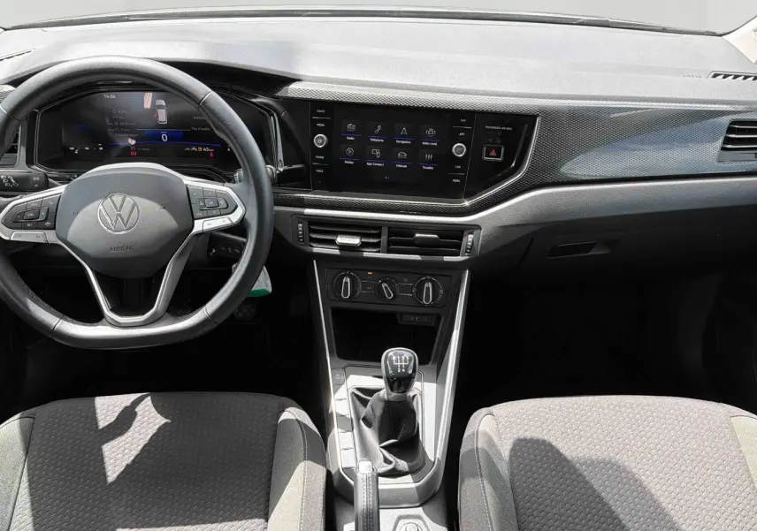 Vue intérieure avant de la Volkswagen Polo 2025 gris, volant multifonctions, écran tactile et levier de vitesse manuel visible.