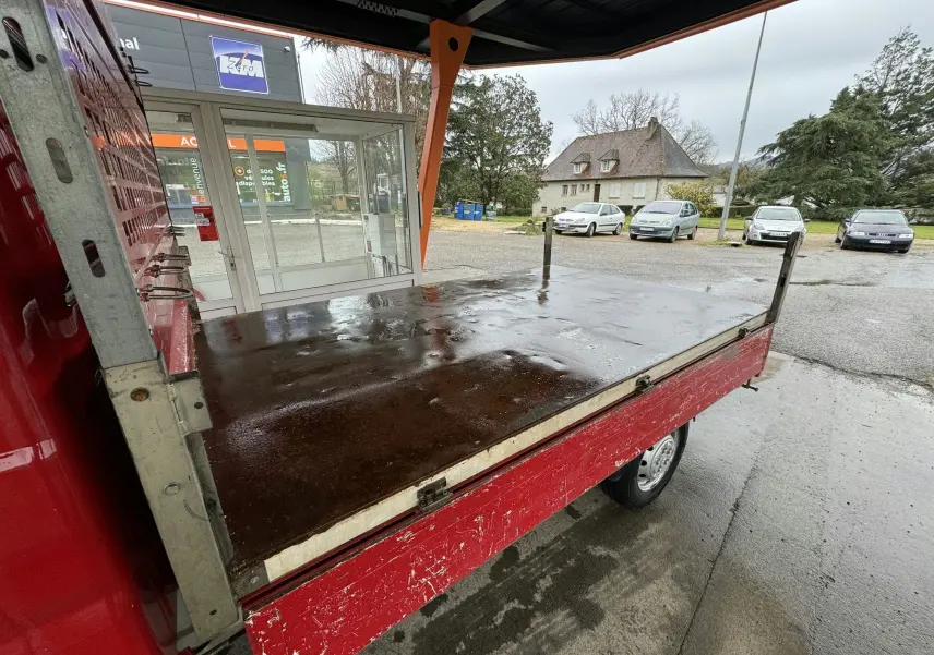 Plateau arrière rouge du Citroën Jumper benne 2019 vu de côté droit sous abri, avec ridelles latérales relevées.