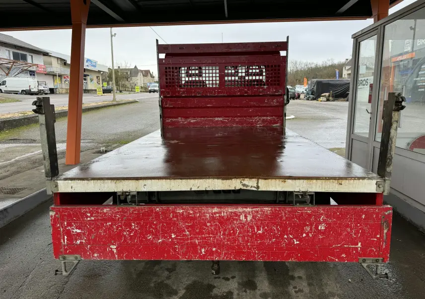 Vue arrière d'une Citroën Jumper benne rouge de 2019 avec ridelles métalliques et plateau usé visible.
