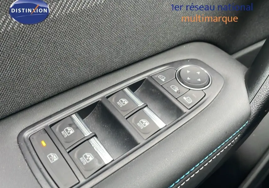 Gros plan sur les commandes des vitres électriques côté conducteur du Renault Symbioz gris Rafale métal, avec surpiqûres bleues.