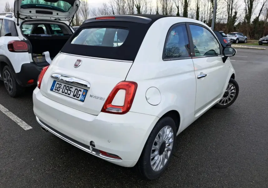 Vue 3/4 arrière droite d'une Fiat 500 Cabriolet blanche avec toit souple noir, immatriculée en France.