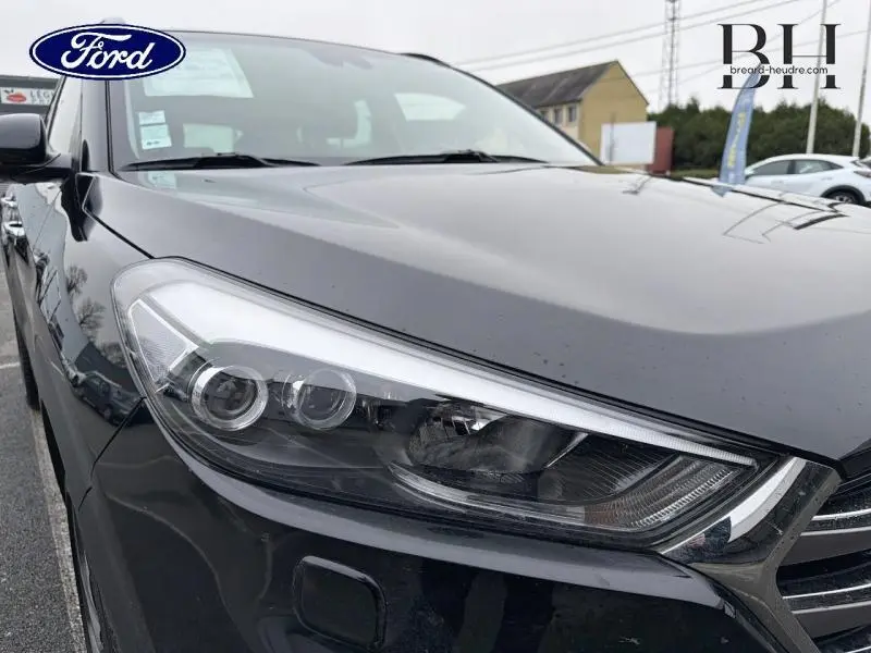 Gros plan sur le phare avant gauche d’un Hyundai Tucson Phantom Black, soulignant la calandre chromée et la teinte noire brillante.