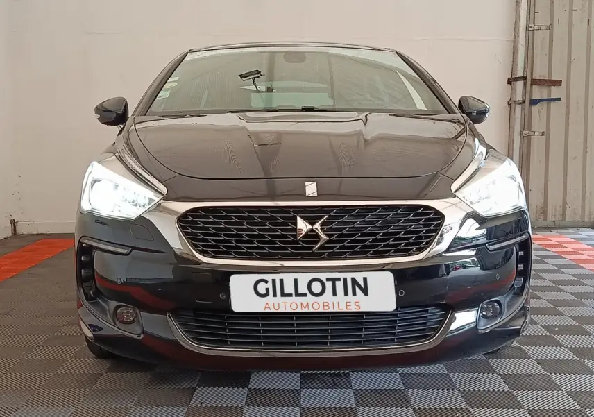 Vue avant d'une DS5 noire avec phares allumés et calandre chromée dans un garage.