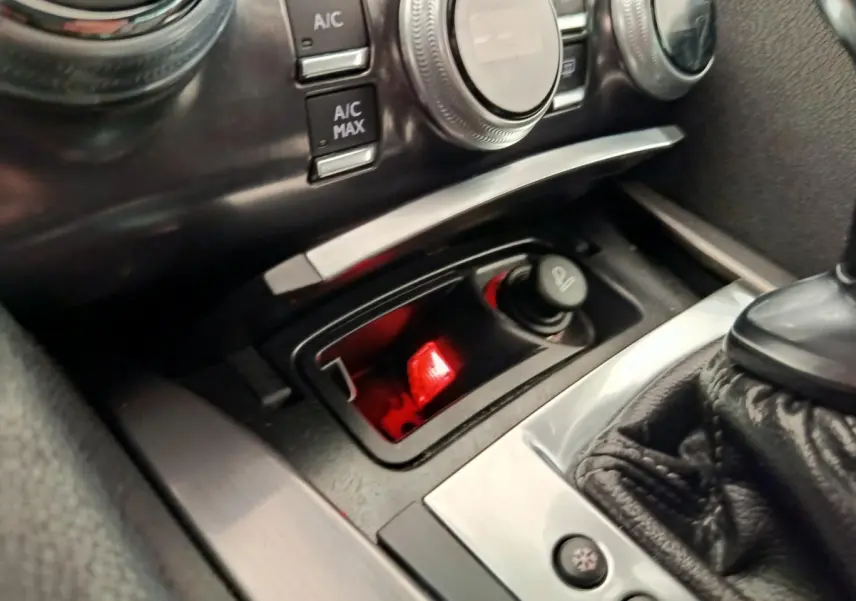 Gros plan intérieur sur la console centrale noire du DS5 avec commandes climatisation et prise allume-cigare éclairée rouge.