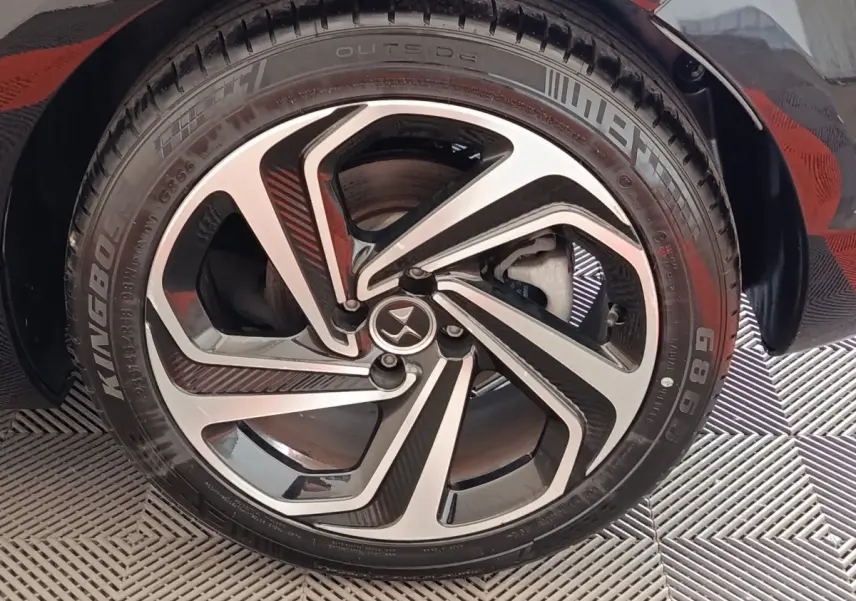 Gros plan sur la roue avant droite noire de la DS5 avec jante alliage bicolore au design moderne.