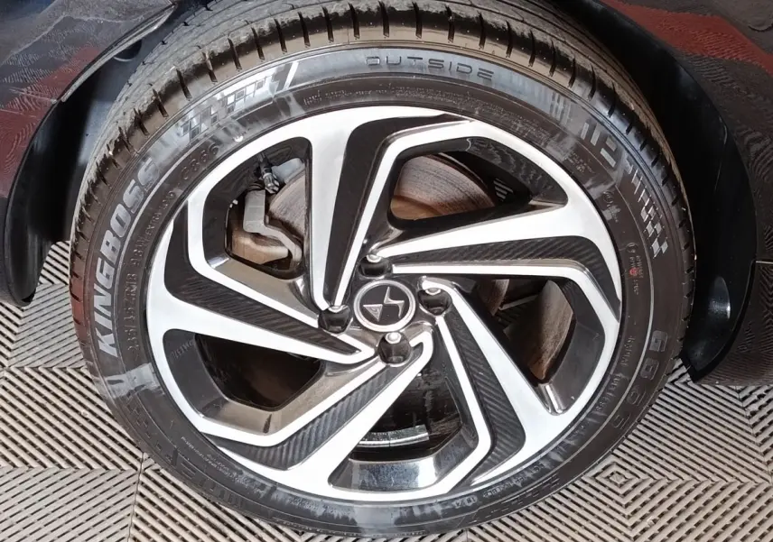 Gros plan sur la roue avant gauche de la DS5 noire, mettant en valeur la jante alliage au design moderne bicolore.