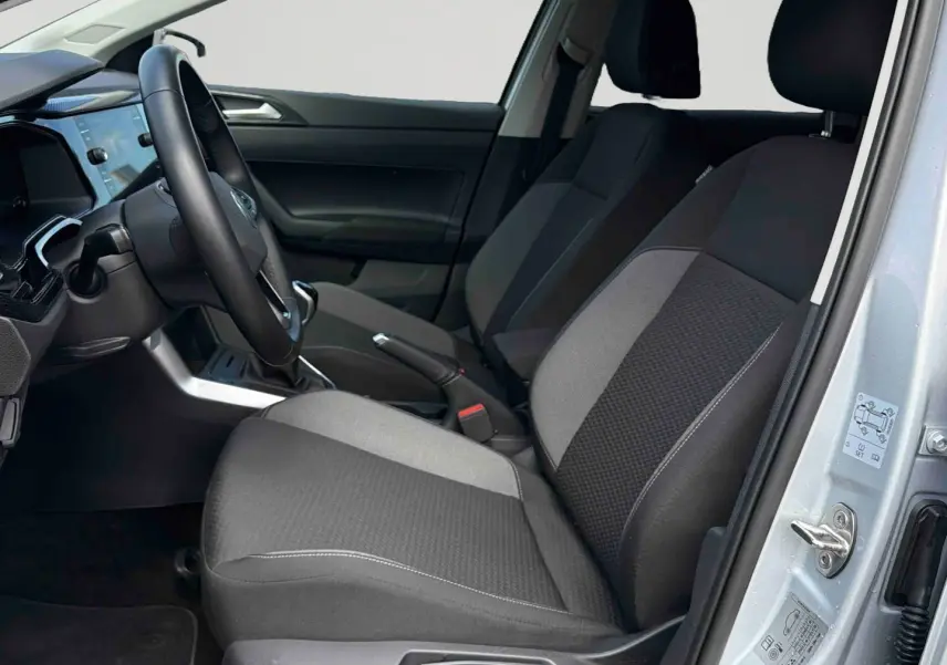 Vue intérieure côté conducteur de la Volkswagen Polo grise 2025, sièges tissu bicolore et volant multifonctions.
