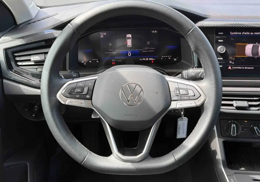 Vue rapprochée du volant multifonctions noir et du tableau de bord digital de la Volkswagen Polo 2025 gris.