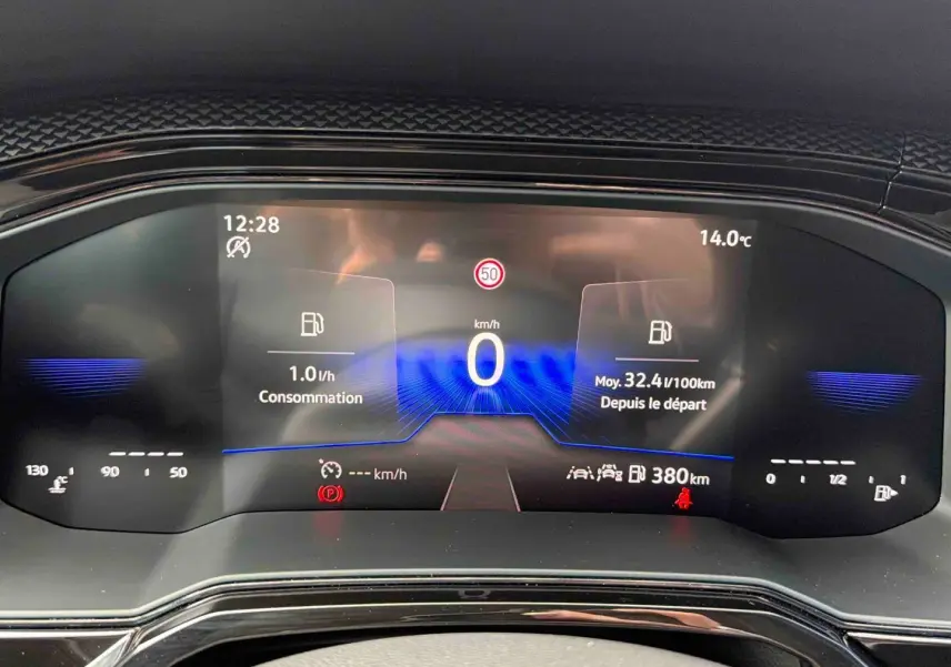 Vue rapprochée du combiné d'instruments digital de la Volkswagen Polo grise, affichant vitesse et consommation.