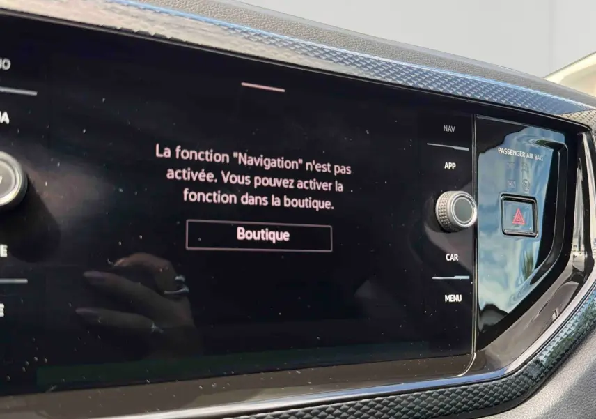Gros plan sur l'écran tactile central noir de la Volkswagen Polo grise, affichant un message d'activation de la navigation.