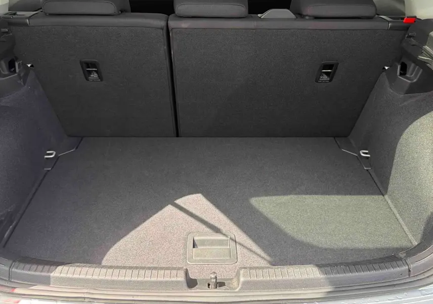 Coffre ouvert vu de l'arrière d'une Volkswagen Polo grise 2025, montrant l'espace de chargement et les dossiers arrière rabattables.