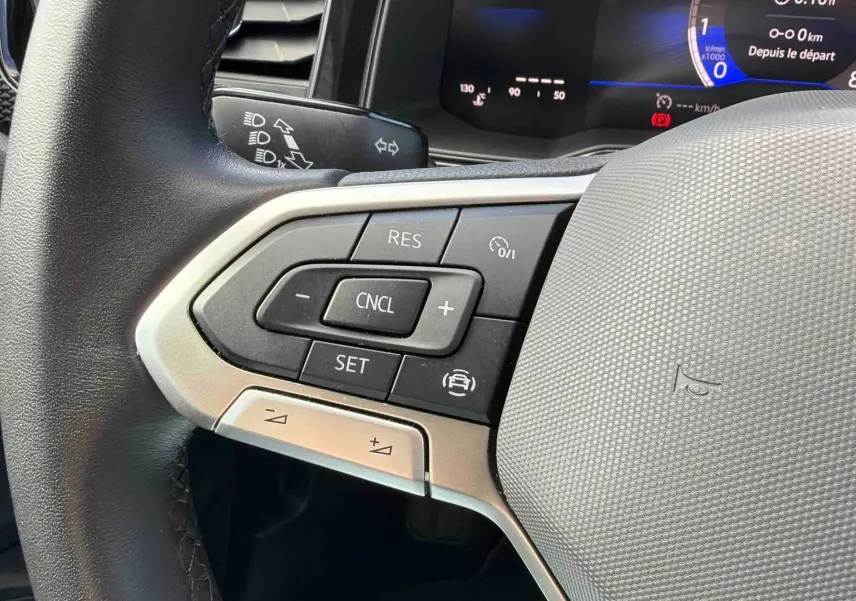 Gros plan sur le volant multifonctions de la Volkswagen Polo 2025, avec commandes de régulateur de vitesse et combiné digital visible.