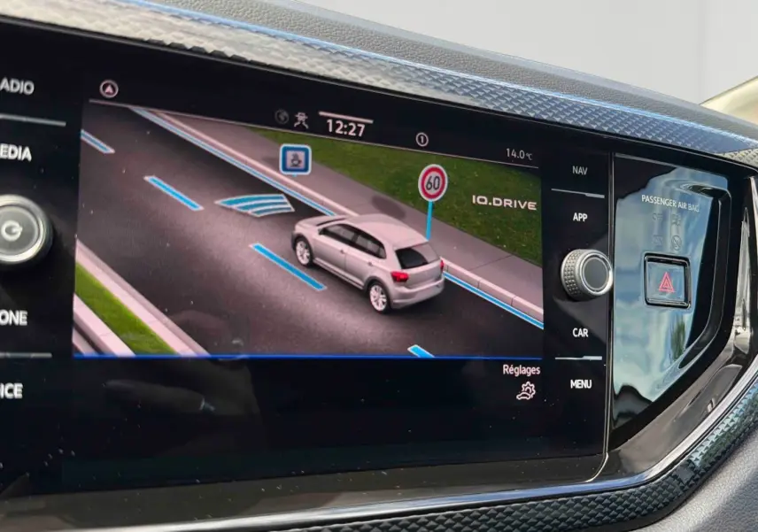 Écran tactile intérieur montrant la Polo grise vue de dessus en simulation de conduite avec signalisation routière.