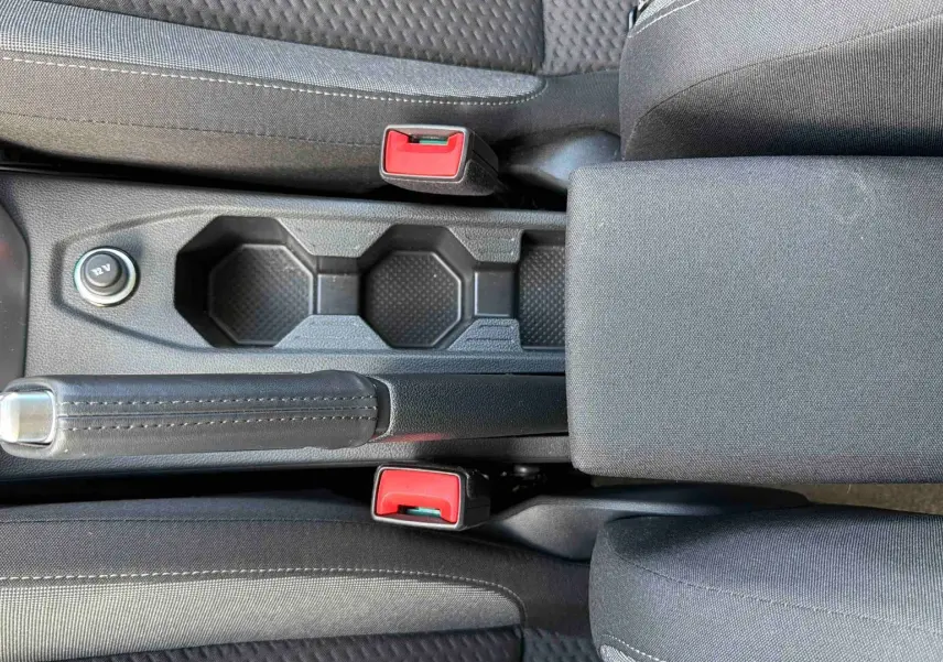 Vue plongeante sur la console centrale noire de la Volkswagen Polo 2025 avec frein à main et accoudoir tissu.