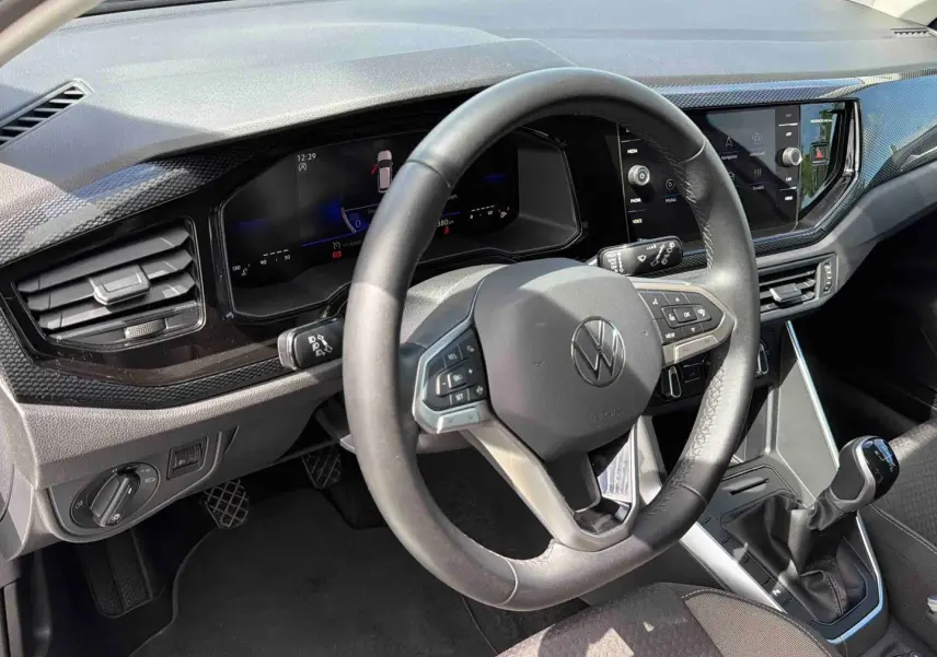 Vue intérieure centrée sur le volant et tableau de bord digital de la Volkswagen Polo grise avec boîte manuelle.