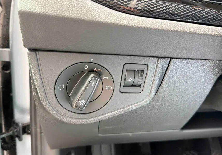 Détail du bouton de commande des phares sur le tableau de bord gris d'une Volkswagen Polo 2025.