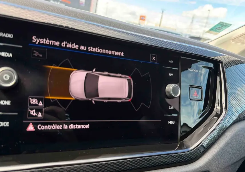 Écran tactile intérieur montrant l'aide au stationnement de la Volkswagen Polo grise, vue de face du tableau de bord.