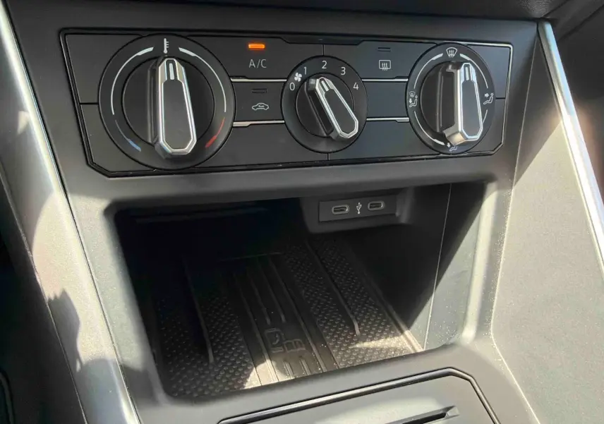 Gros plan sur la console centrale de la Volkswagen Polo grise, montrant les commandes de climatisation manuelle et ports USB-C.