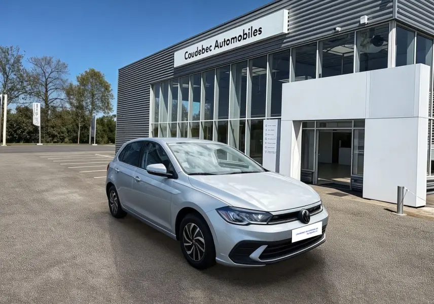 Volkswagen Polo grise vue 3/4 avant droite devant un bâtiment de concession Coudebec Automobiles.