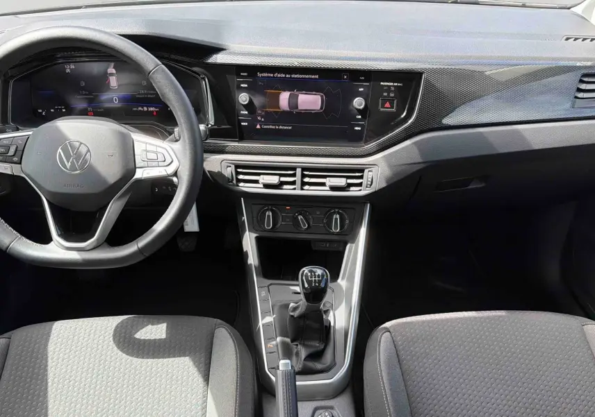 Vue intérieure avant de la Volkswagen Polo grise 2025, avec tableau de bord digital et levier de vitesses manuel.