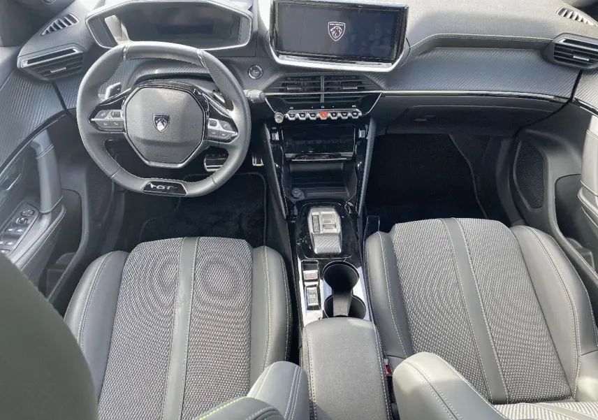 Vue intérieure avant du Peugeot 2008 noir, mettant en valeur le volant GT, l'écran tactile et les sièges en cuir gris.
