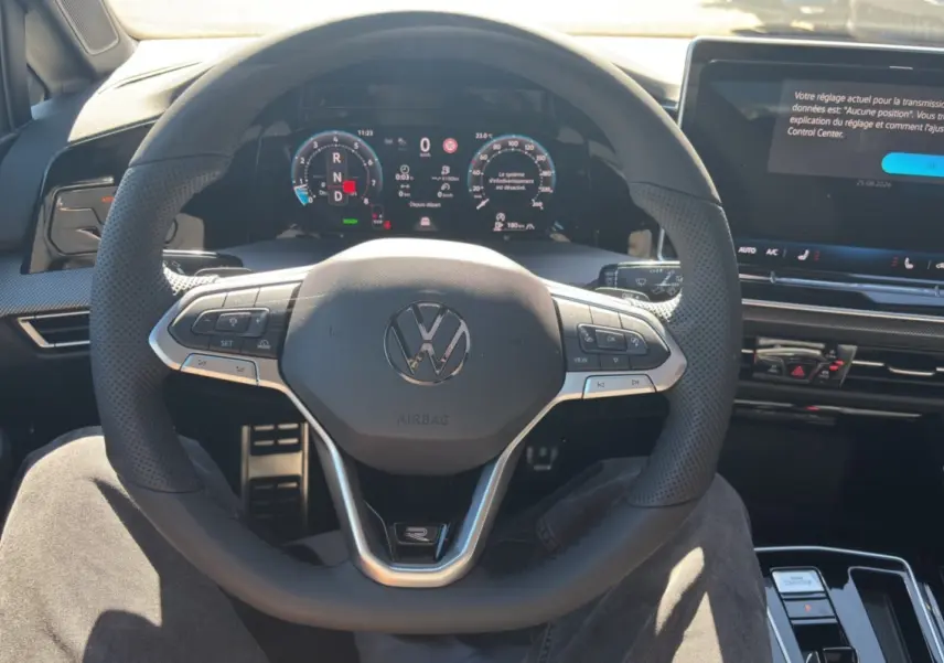 Vue intérieure centrée sur le volant cuir multifonctions et le tableau de bord numérique d'une Volkswagen Golf TDI 150 R-Line.