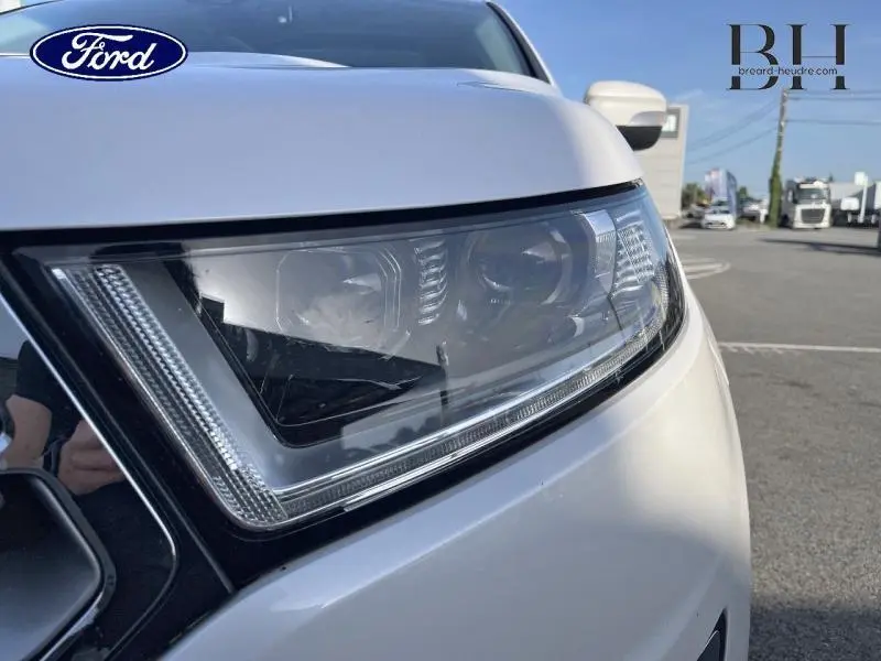 Gros plan sur le phare avant droit du Ford Edge blanc Platinum, mettant en valeur le design LED dynamique.