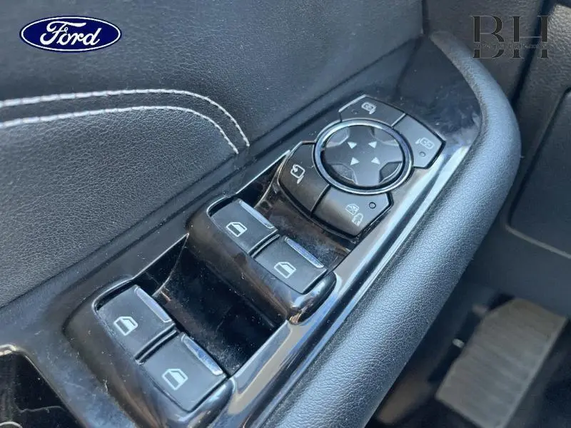 Gros plan sur les commandes de lève-vitres et rétroviseurs côté conducteur en cuir noir du Ford Edge blanc Platinum 2016.