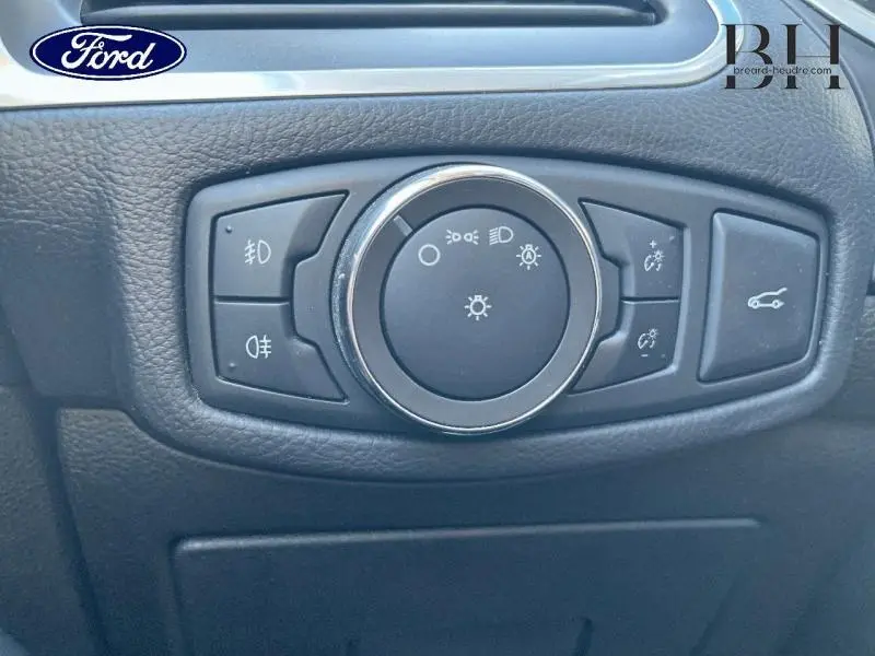 Gros plan sur le sélecteur de phares et commandes d’éclairage du tableau de bord noir du Ford Edge blanc Platinum 2016.
