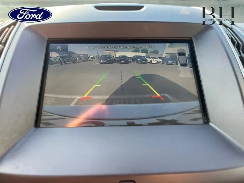 Vue de l'écran de caméra de recul du Ford Edge blanc Platinum montrant l'arrière avec lignes de guidage colorées.