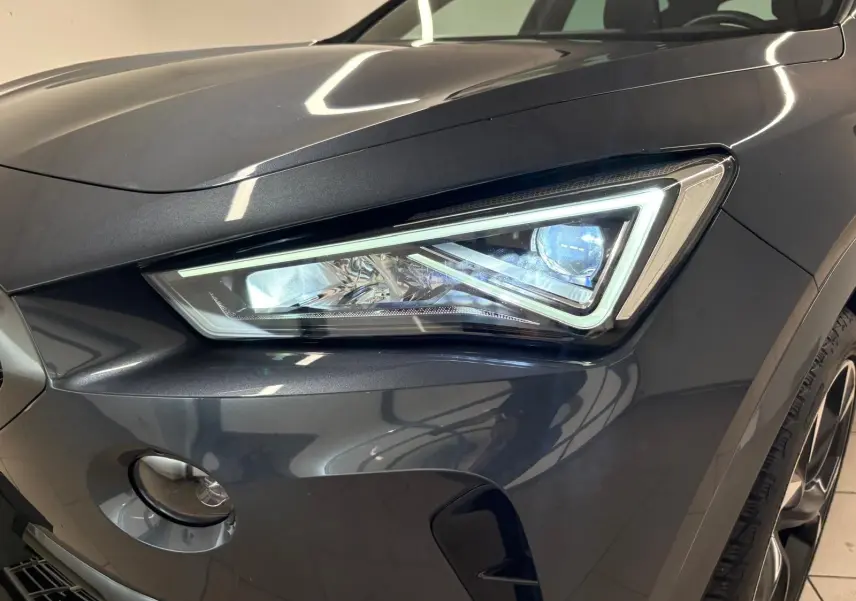 Gros plan sur le phare avant droit du CUPRA Formentor gris magnétique, soulignant son design anguleux et moderne.