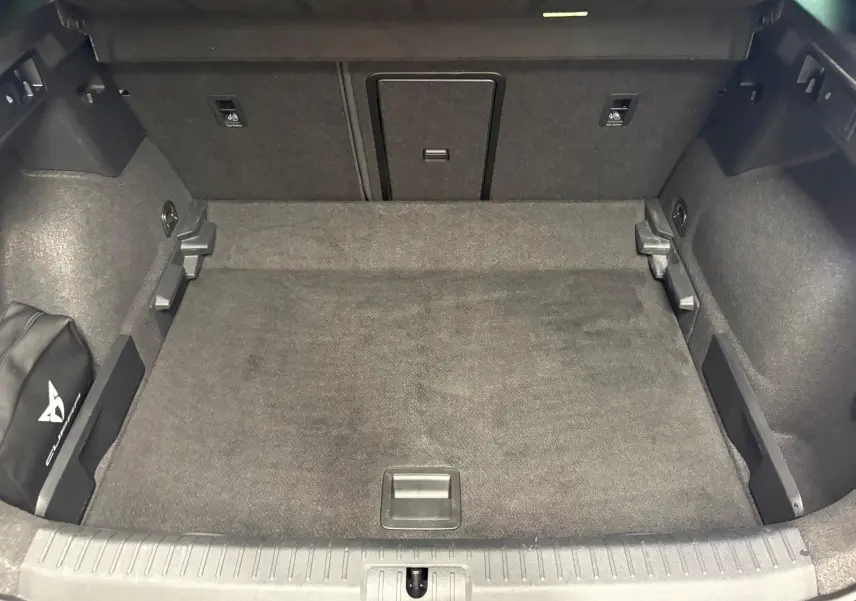 Coffre spacieux du CUPRA Formentor gris magnétique vu de l'arrière, avec tapis de sol et rangement latéral marqué Cupra.