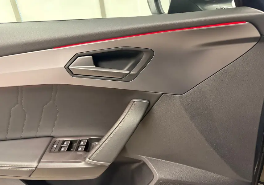Gros plan sur la porte intérieure côté gauche du CUPRA Formentor 2023 avec surpiqûres et bande lumineuse rouge.