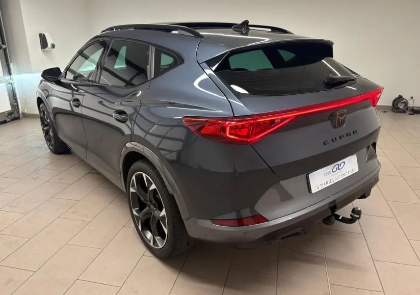 Vue 3/4 arrière droite d'un CUPRA Formentor gris magnétique 2023 avec feux arrière LED et attelage visible