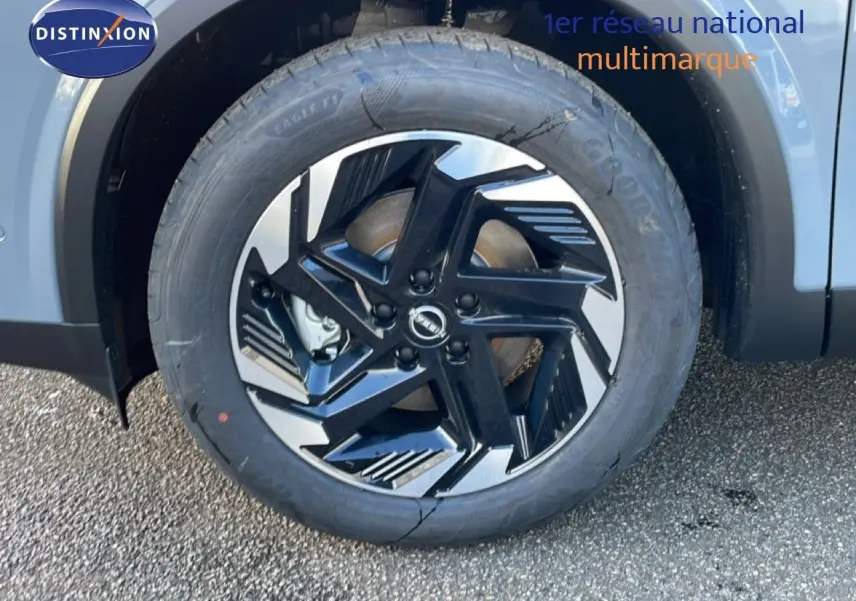 Gros plan sur la roue avant gauche du Nissan Qashqai 2025 gris argile métal avec jante alliage noire et argent.