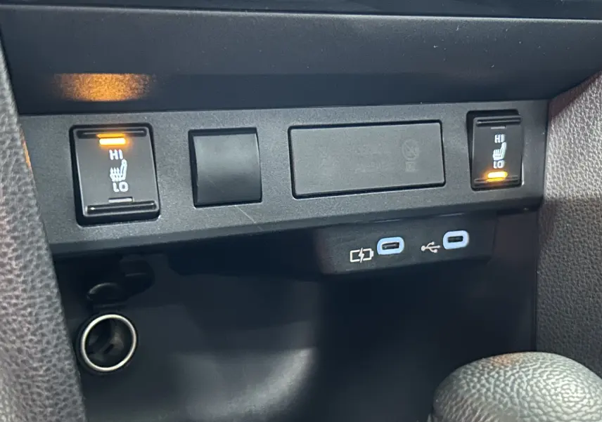 Gros plan sur les commandes des sièges chauffants et ports USB dans l’habitacle noir de la Toyota Yaris Cross 2025.