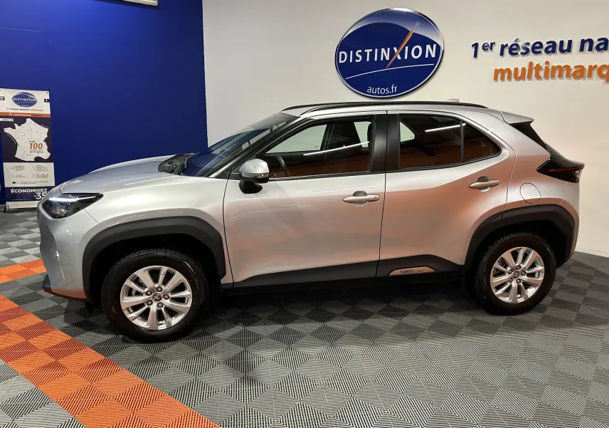 Vue de profil côté gauche d'une Toyota Yaris Cross 116h Active gris minéral, avec jantes alliage et protections noires.