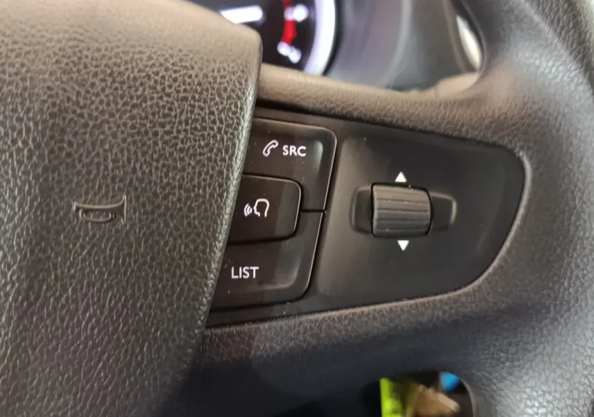 Gros plan sur les commandes noires du volant du Peugeot Expert Fourgon blanc, avec boutons SRC et liste visibles.