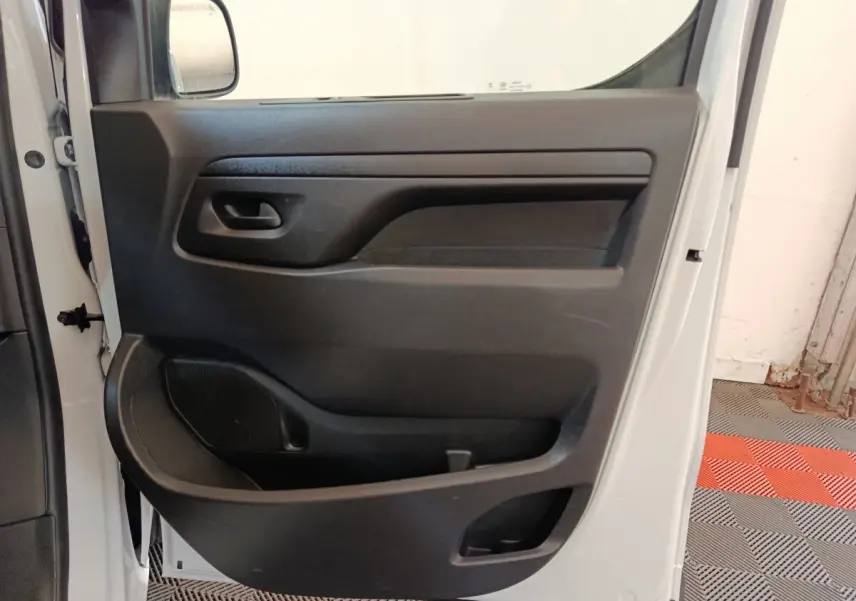 Vue intérieure de la porte côté gauche du Peugeot Expert Fourgon blanc, avec panneau de porte noir et poignée intégrée.
