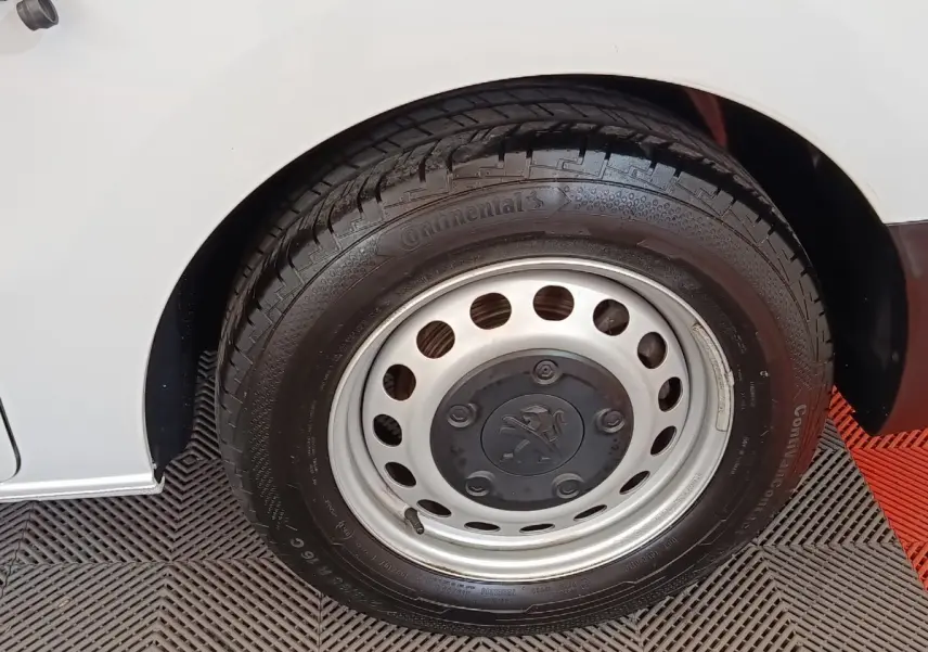 Gros plan sur la roue arrière droite d’un Peugeot Expert Fourgon blanc, jante acier avec logo Peugeot central.