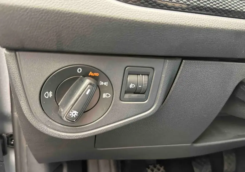 Détail du tableau de bord côté gauche avec commande d’allumage automatique des phares sur Volkswagen Polo grise 2025.