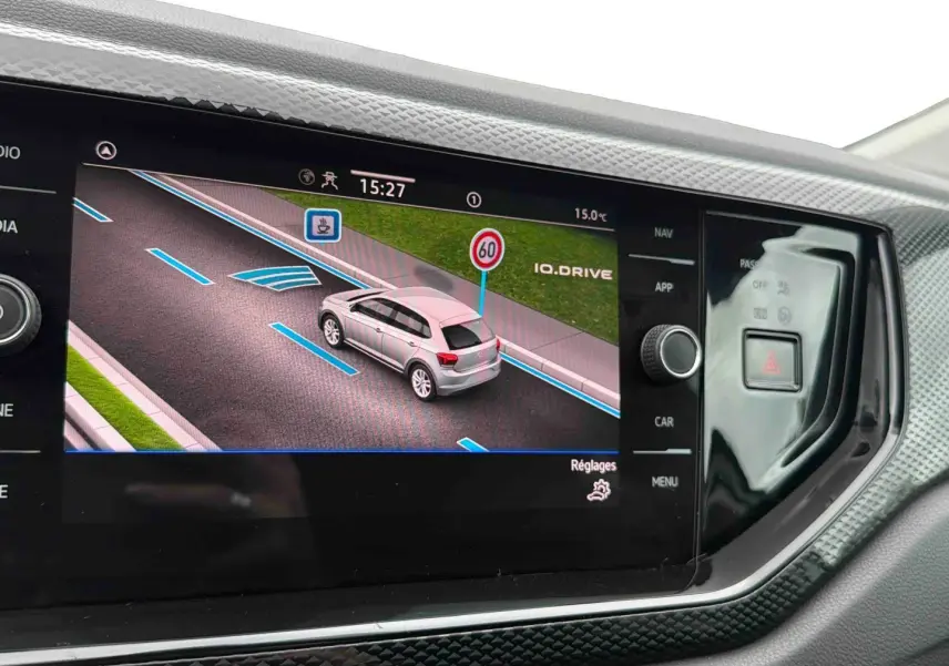 Écran tactile intérieur montrant l’interface de conduite assistée avec une Polo grise vue de trois quarts arrière.