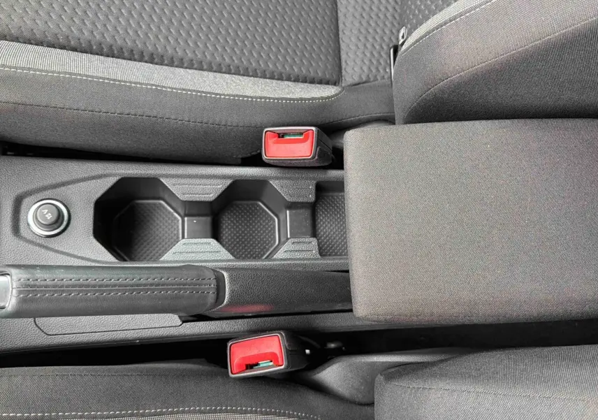 Vue rapprochée de la console centrale grise de la Volkswagen Polo 2025 avec accoudoir et porte-gobelets.