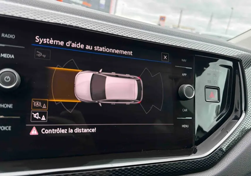 Écran tactile intérieur montrant l’aide au stationnement avec vue arrière de la Volkswagen Polo grise 2025.
