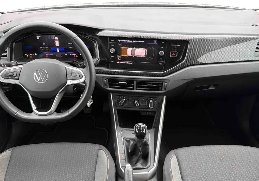 Vue intérieure frontale de la Volkswagen Polo grise 2025, avec tableau de bord digital et levier de vitesse manuel.