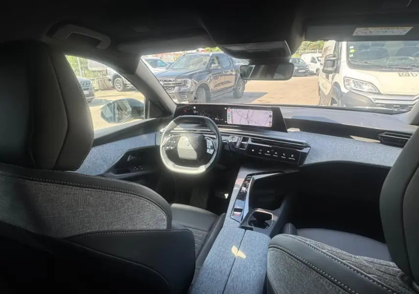 Vue intérieure avant du Peugeot 3008 Hybrid 136 e-DCS6 Allure 2025, avec cockpit numérique et sellerie grise.